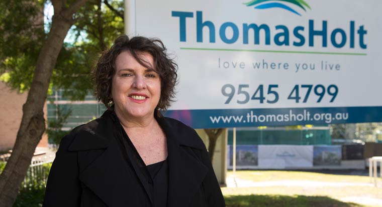 Chief Executive Alexandra Zammit stands in front of a Thomas Holt sign